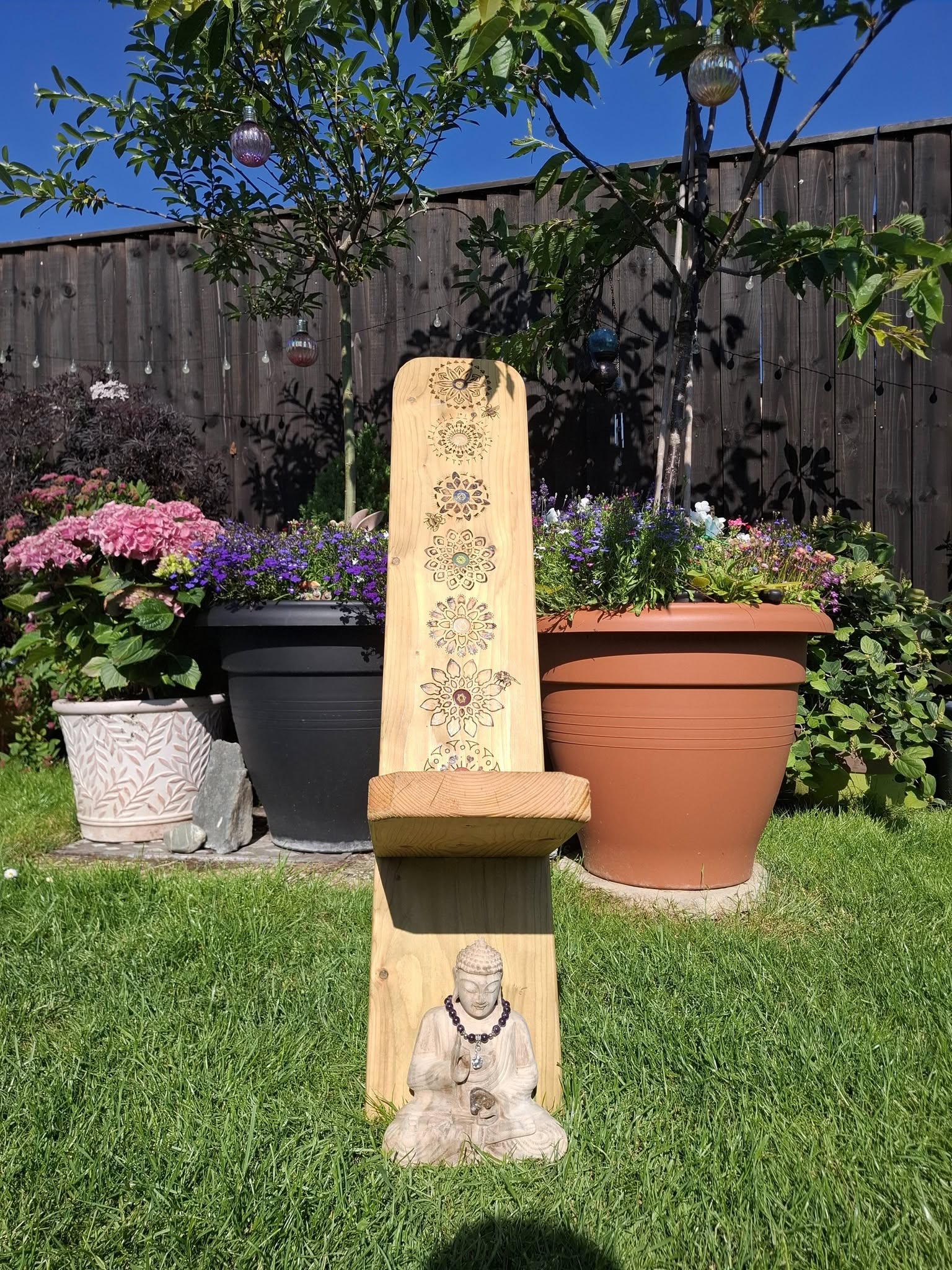 A wooden garden sculpture with Buddha and mandala designs